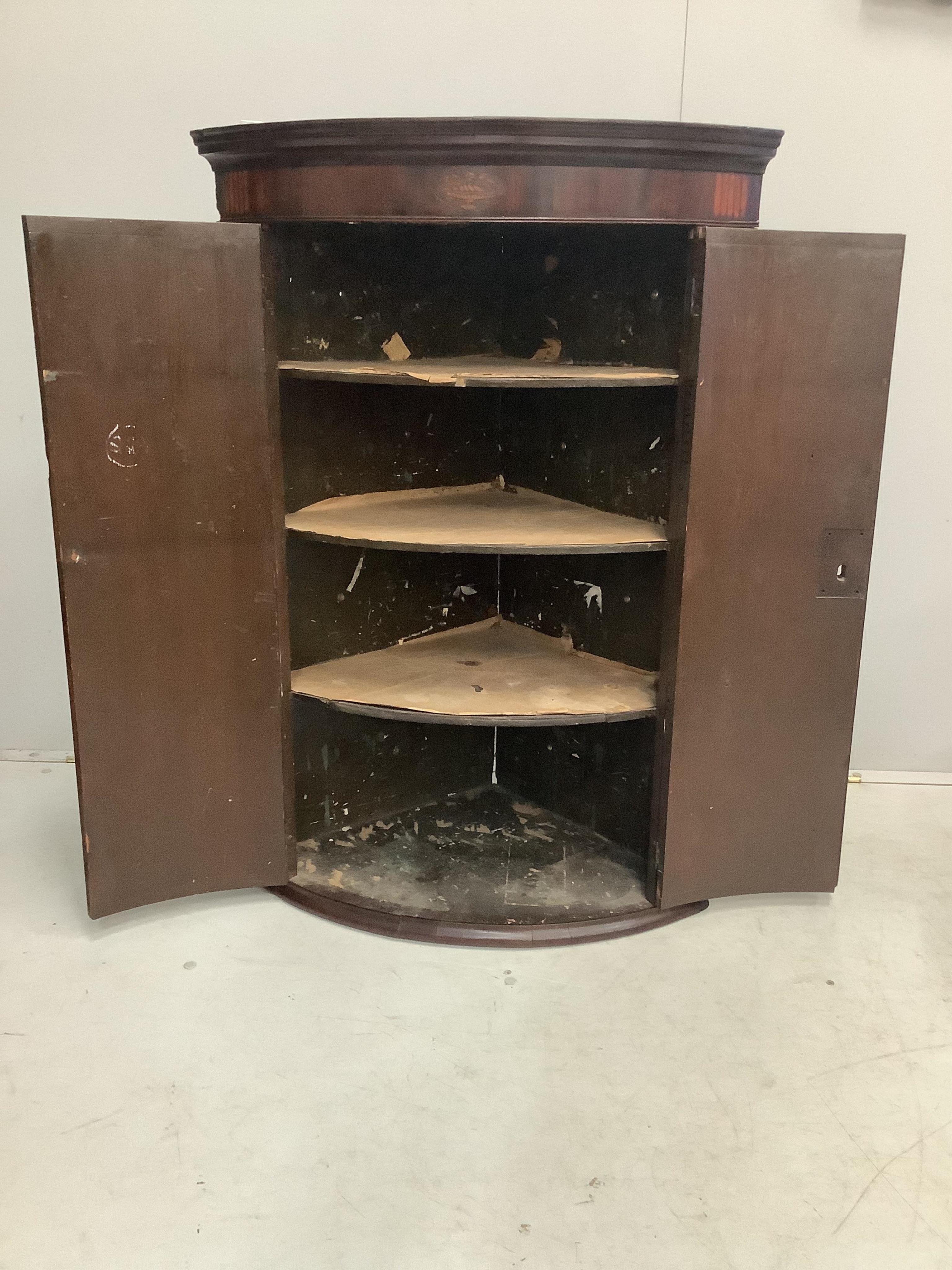 A George III inlaid mahogany bow front hanging corner cupboard, width 74cm, depth 50cm, height 107cm